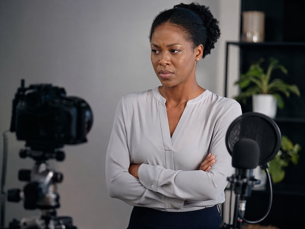 A business owner standing stiffly in front of a tripod and microphone
